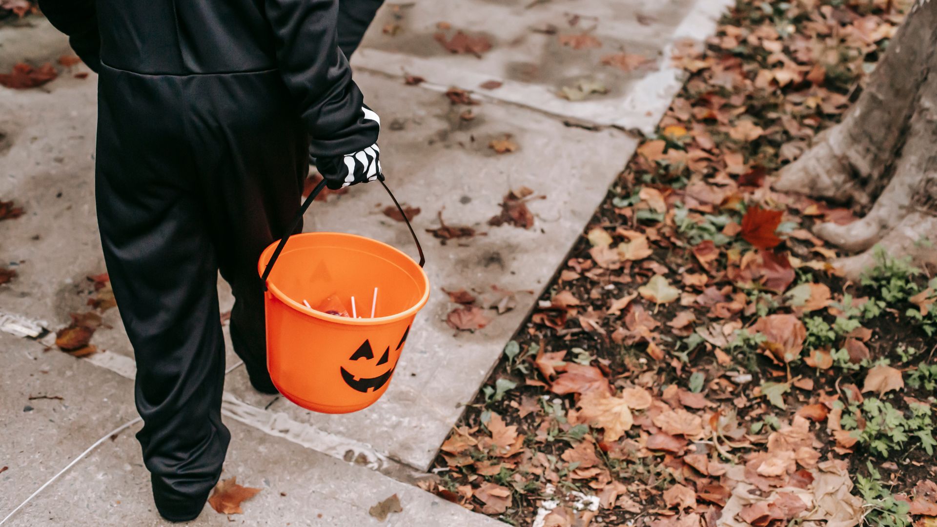 kid in costume walking with a halloween pail